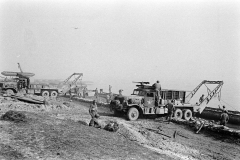 Unloading treadway bridge sections from Brockway B666 6x6 bridge erector trucks, possibly belonging to 17thAEB